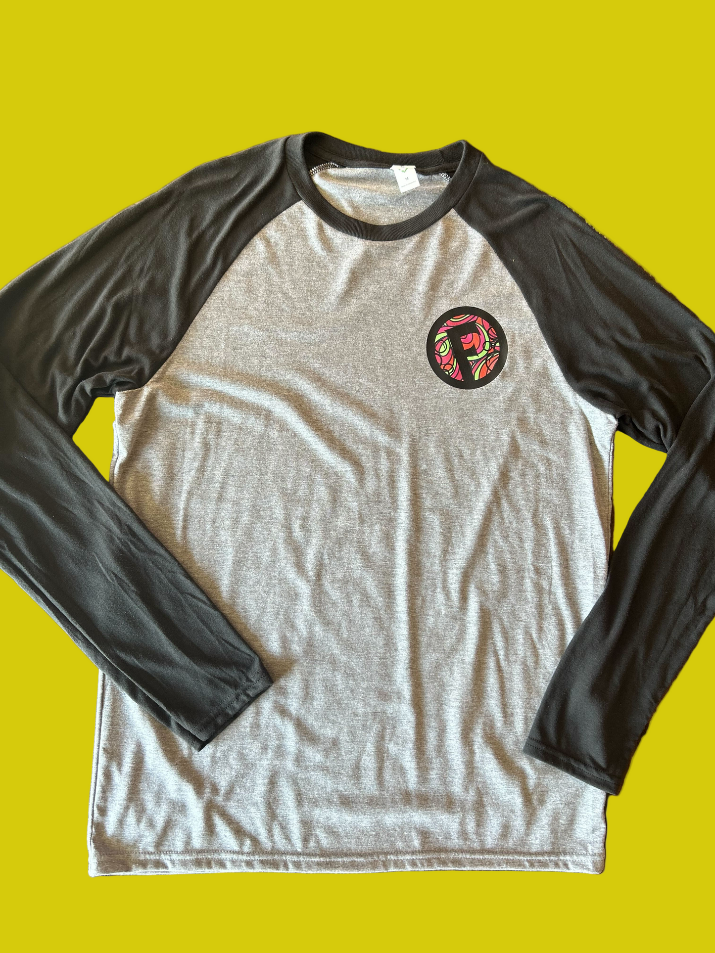 Gray and black long-sleeve shirt with a circular logo on a yellow background